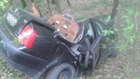 rozbity samochód marki VW passat w przydrożnym rowie wśród drzew