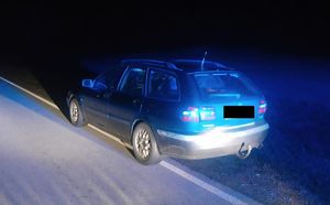 Na zdjęciu widoczny jest stojący na drodze samochód osobowy marki Volvo koloru ciemnego typu kombi. Zdjęcie jest zrobione w porze nocnej.